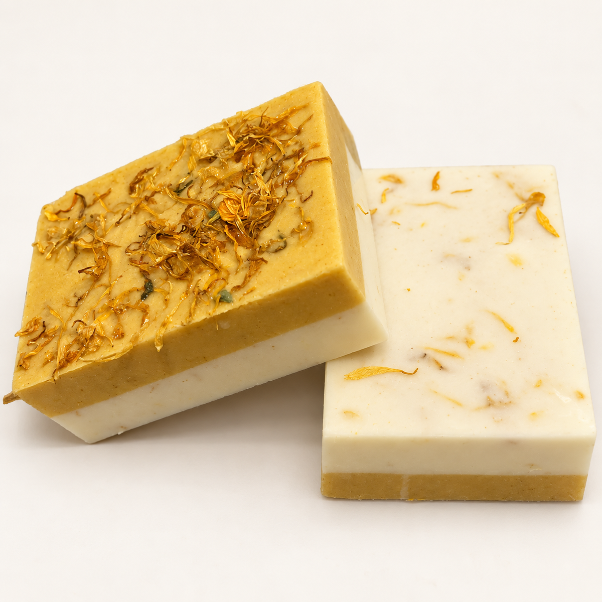 RENATURALS Buffing Bars in the earlier flat design, showing an ivory layer and a turmeric-gold lower half with calendula petals on a warm ivory background.