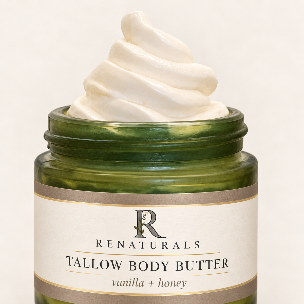 Close-up of creamy ivory whipped Tallow Body Butter in a green glass jar with the RENATURALS Botanical R label and soft gold trim.